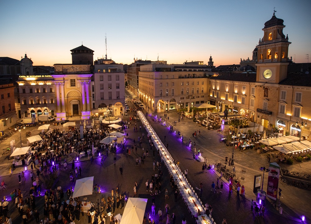 Spettacolare veduta serale di Parma in Emilia, con "La Cena dei Mille" illuminata in Piazza Garibaldi, esperienza di cultura e lifestyle.