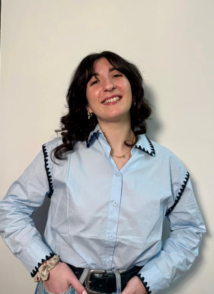 Ritratto di Camilla sorridente con camicia azzurra e mani sui fianchi, membro del team Food Valley Travel.